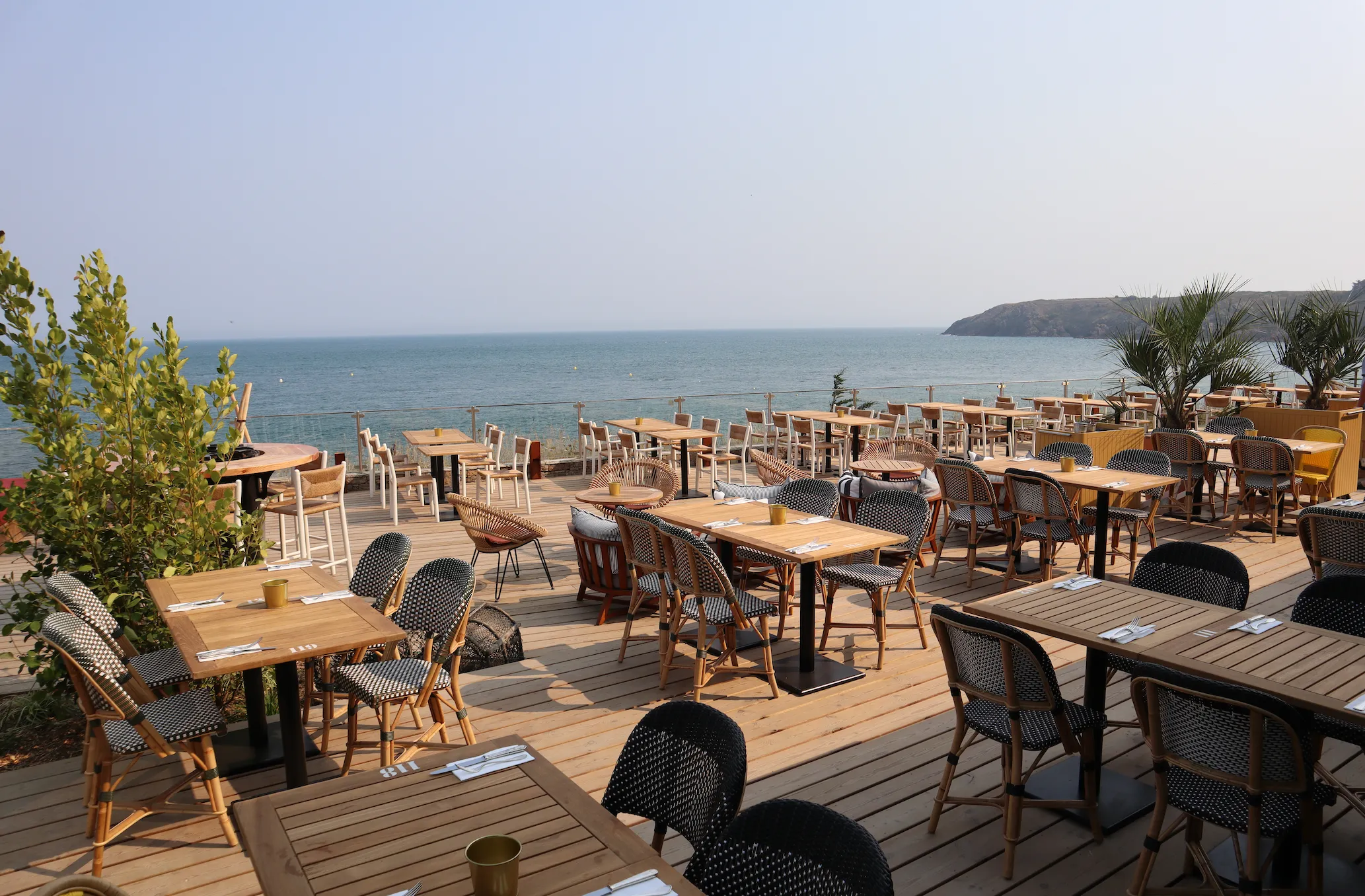 La terrasse en bois de Colette face à la mer, tables dressées au soleil