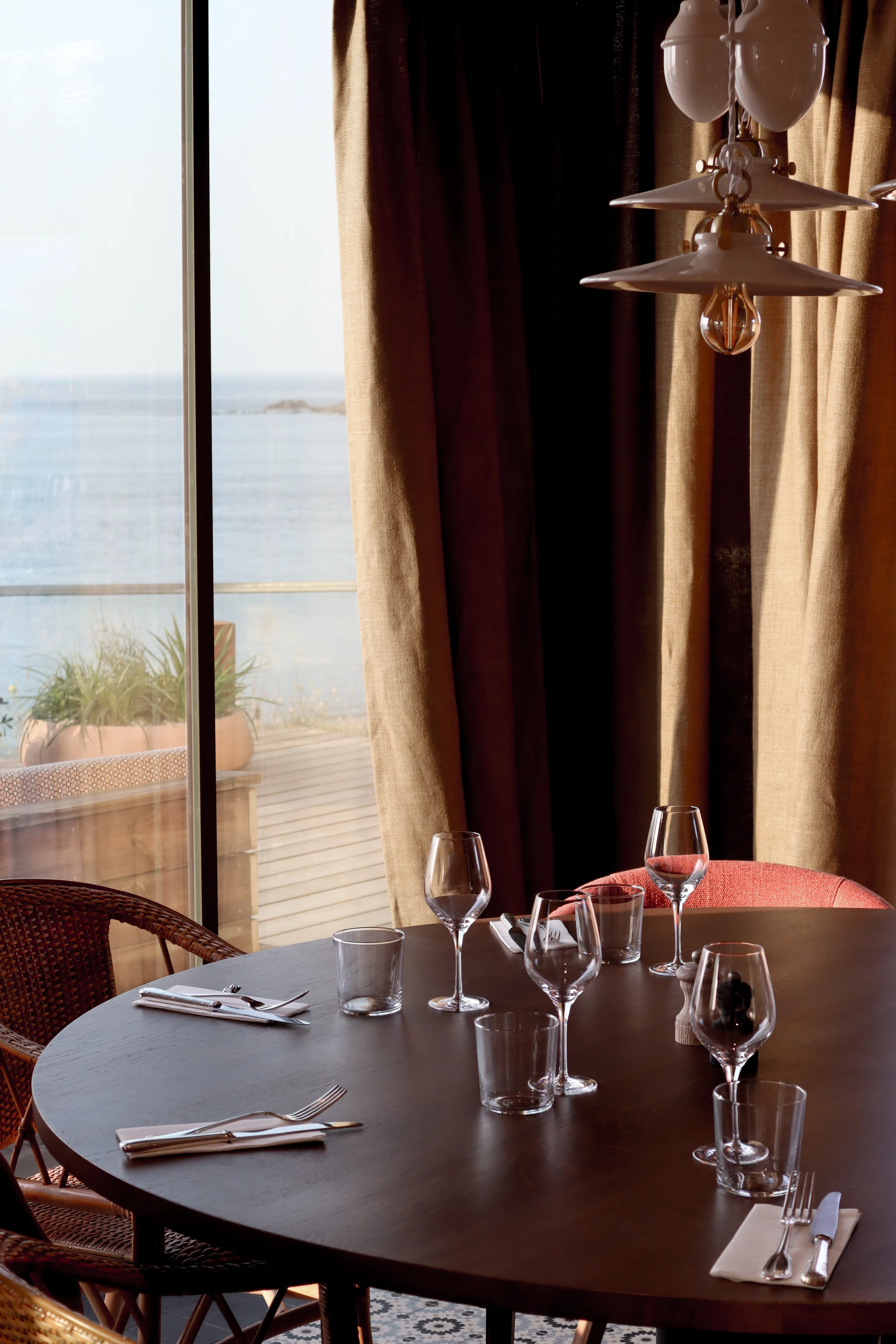 Table dressée près de la baie vitrée, la mer en toile de fond