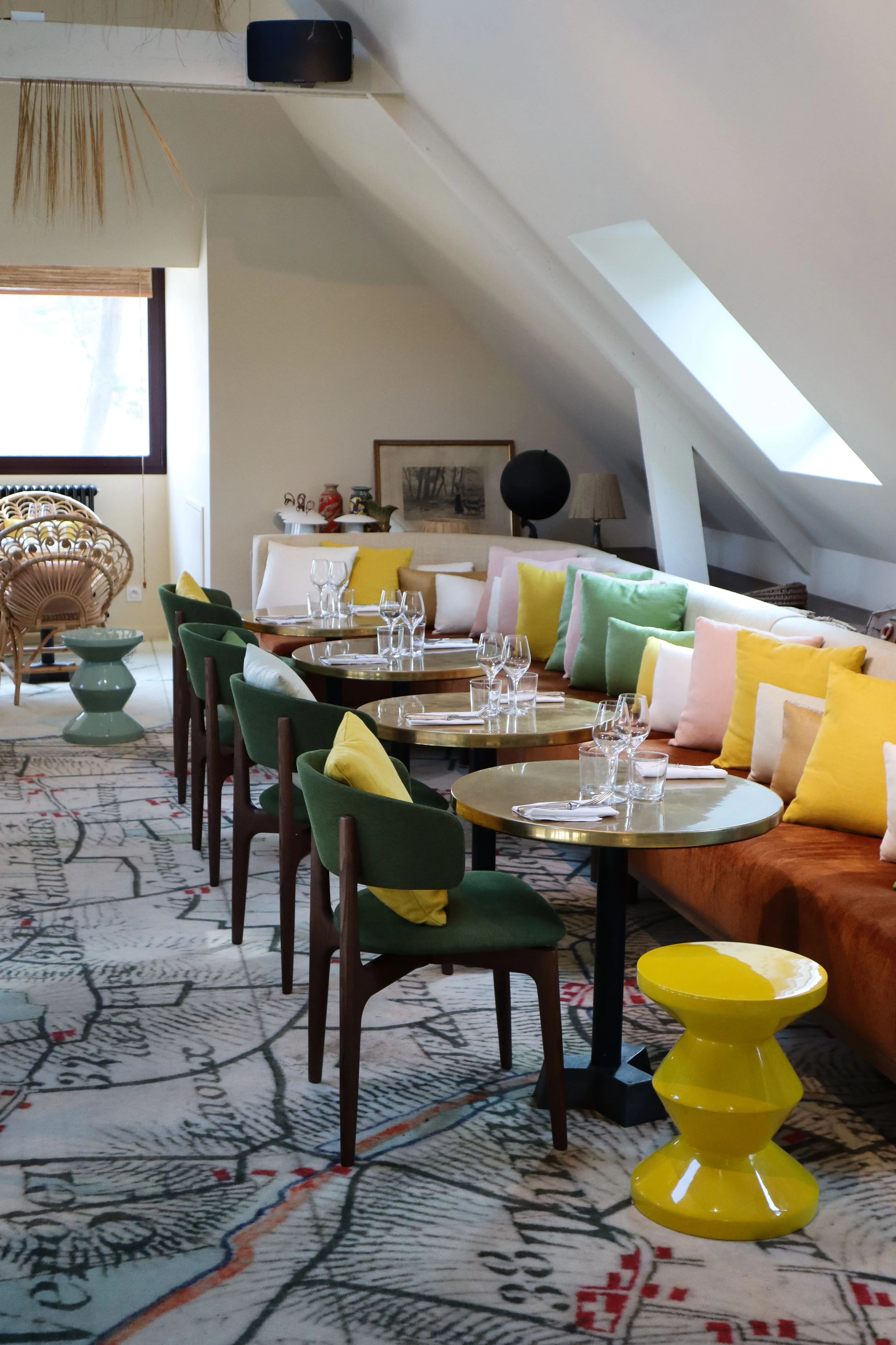 Le salon mansardé sous les combles, banquettes et tables vertes