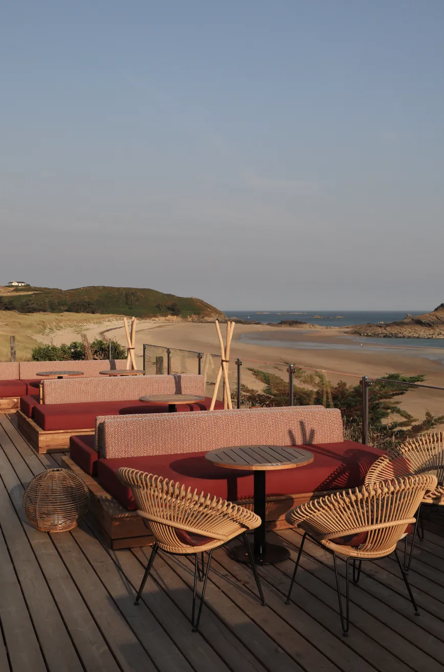 Banquettes terracotta de la terrasse, face à la plage des Chevrets