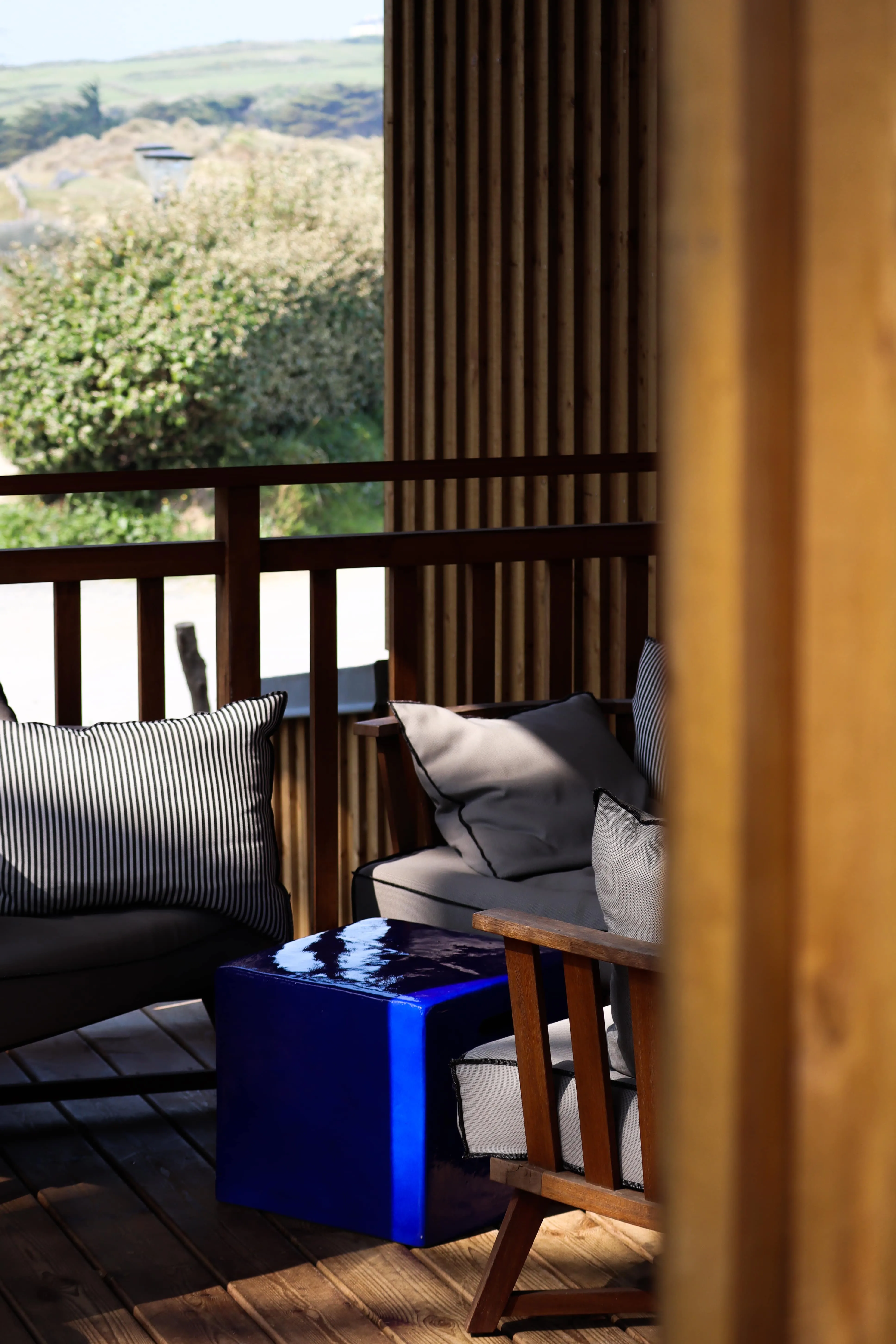 Le salon de la terrasse, tabouret bleu et banquettes au soleil